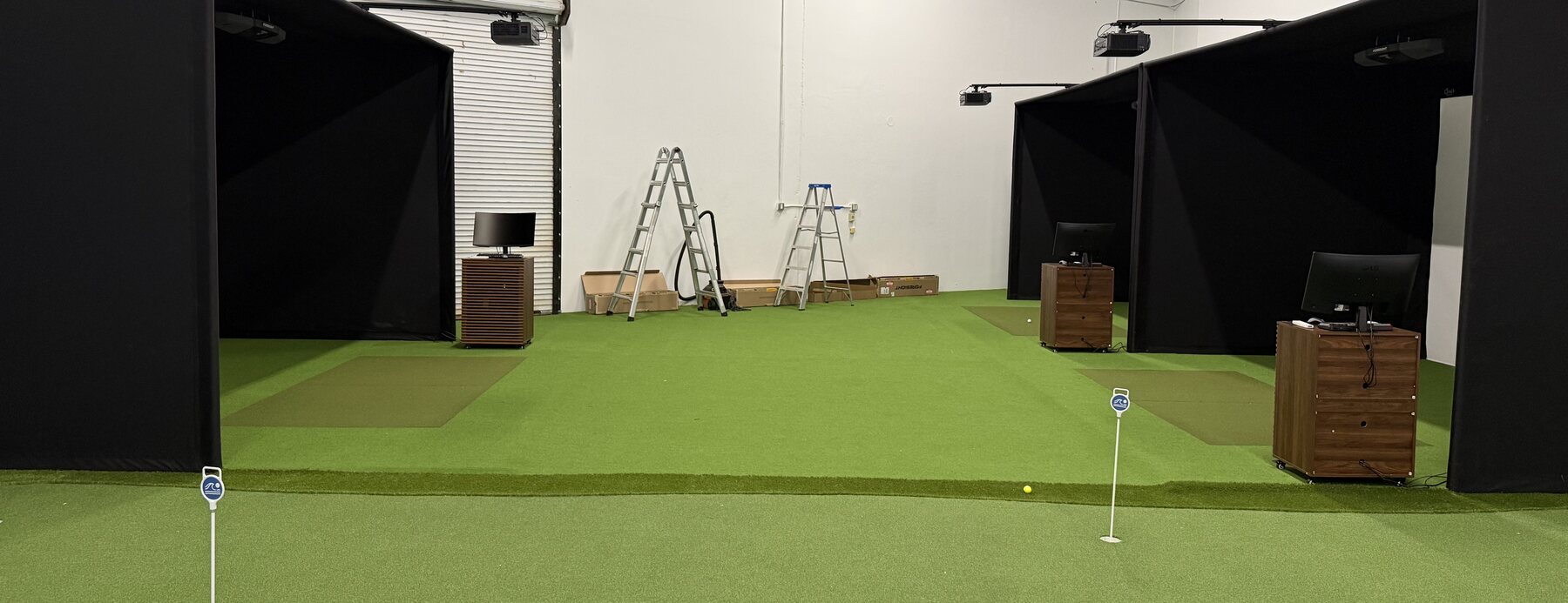 Four modular simulator enclosures under overhead projectors in a commercial space.