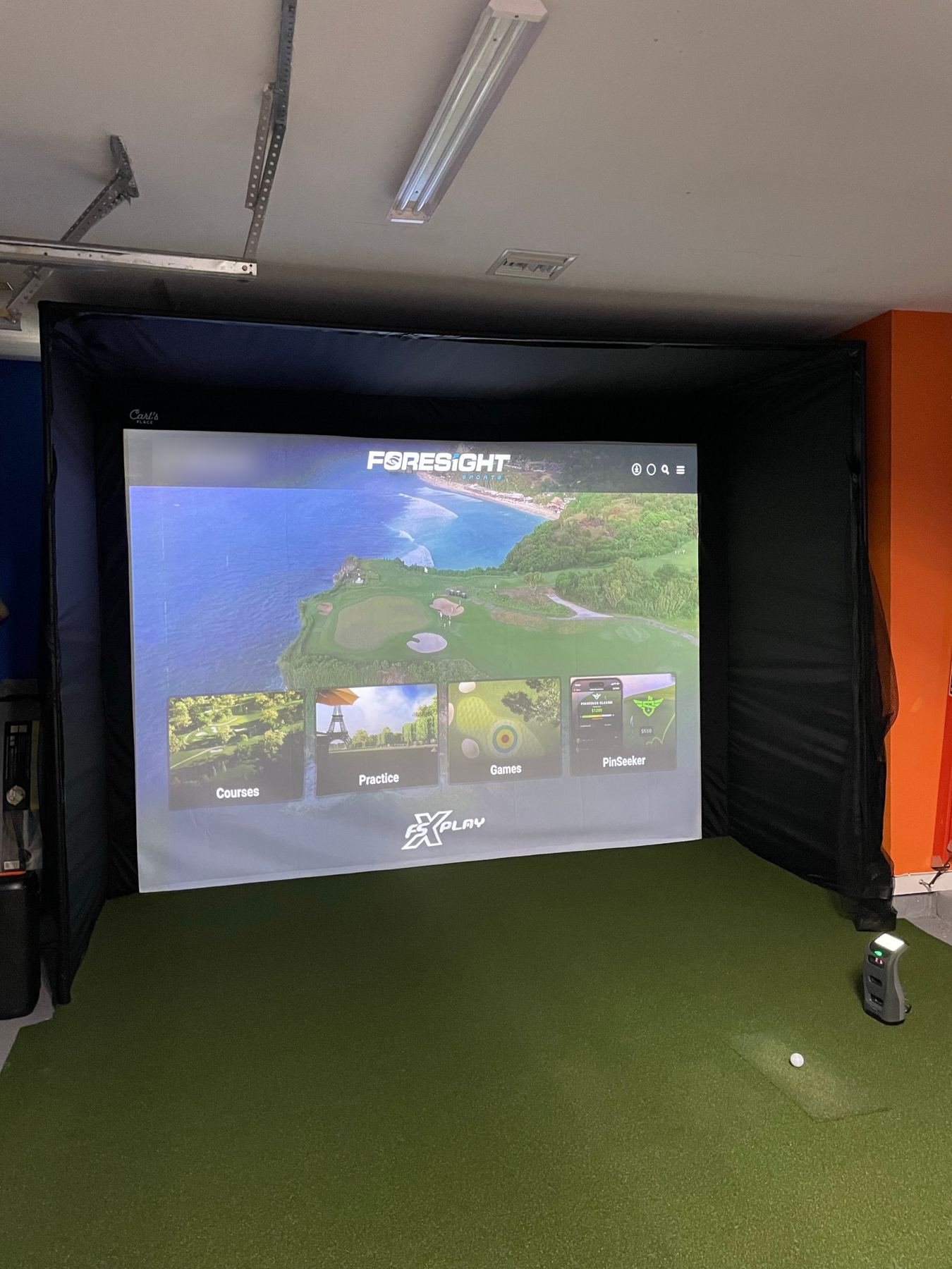 Modular enclosure in a garage with a floor-side launch monitor.