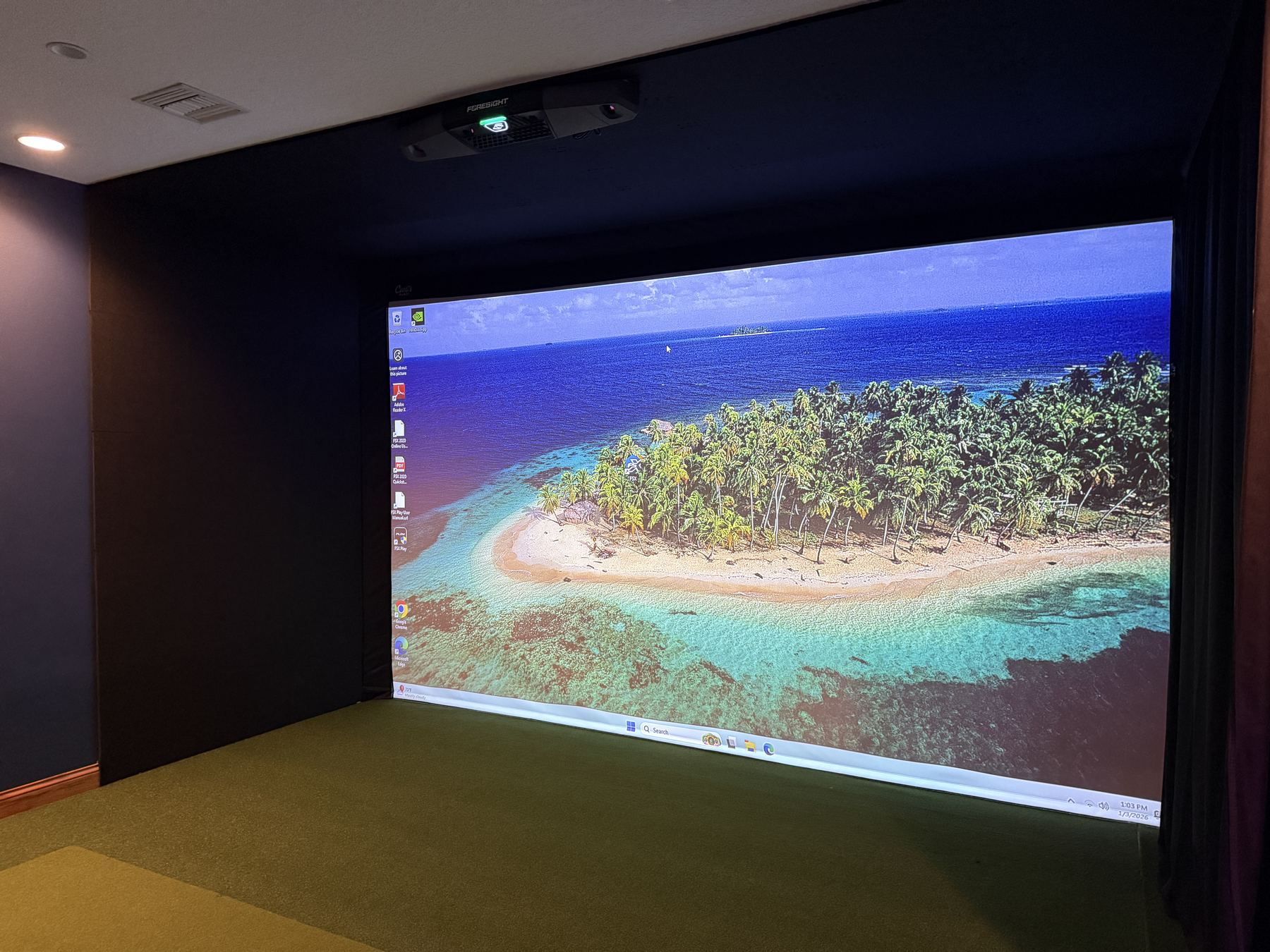 Simulator built into a dark media room with an overhead Foresight unit and wall-to-wall screen.