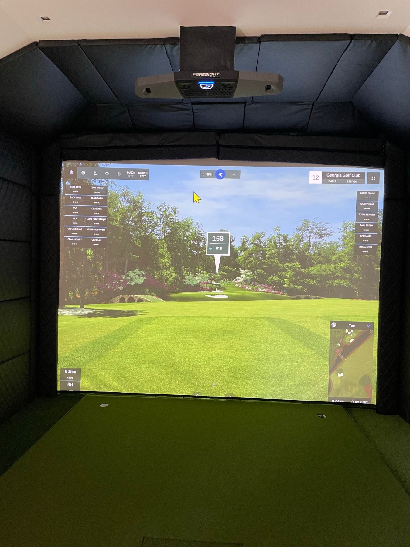A custom built-in simulator room with padded walls and ceiling and an overhead launch monitor.
