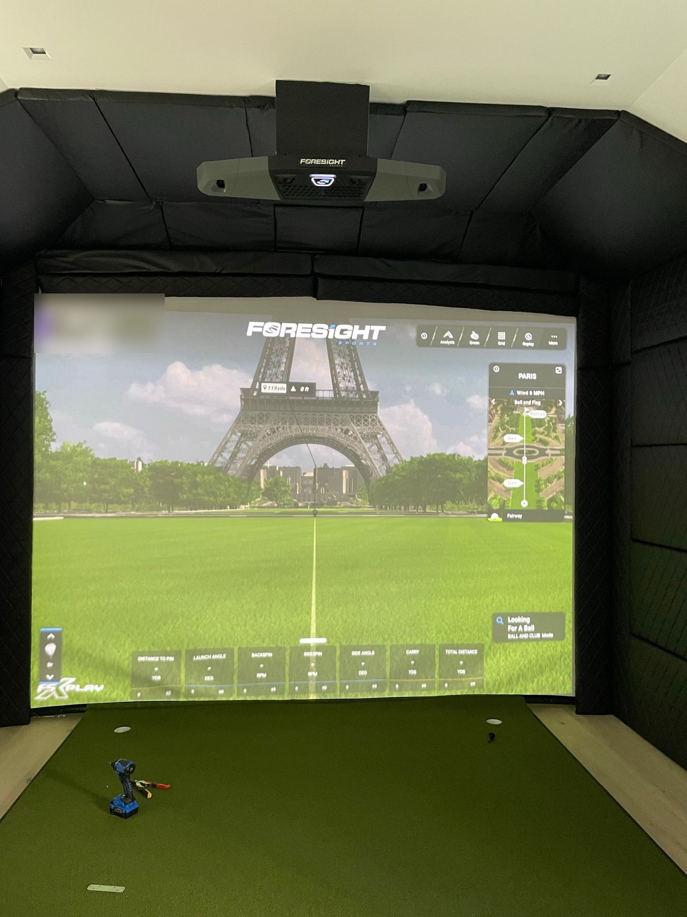 Padded simulator room at handover, with a drill still on the turf and the overhead unit mounted above.