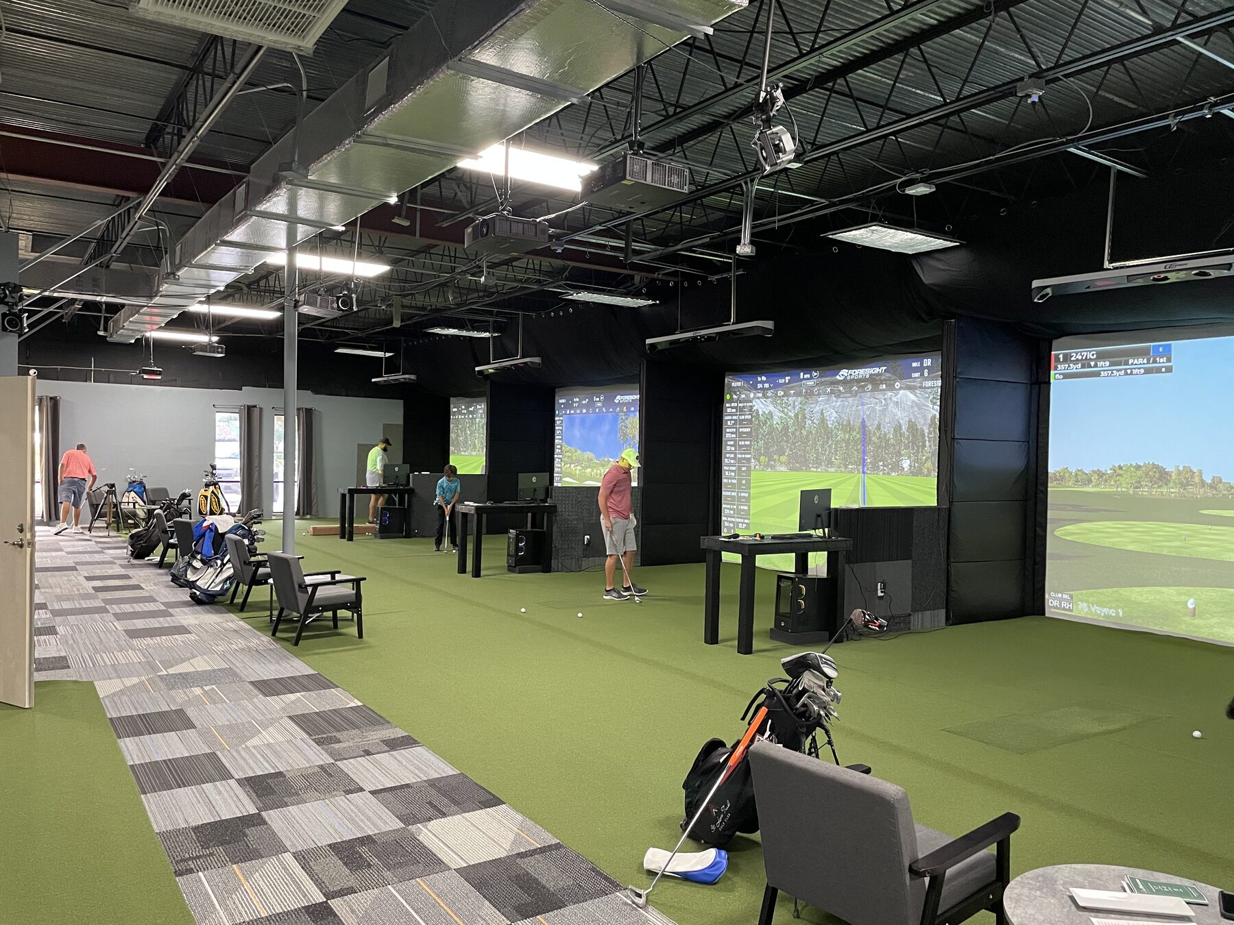 Inside 247 Indoor Golf, the Pro-Sims showroom, with lit simulator screens.